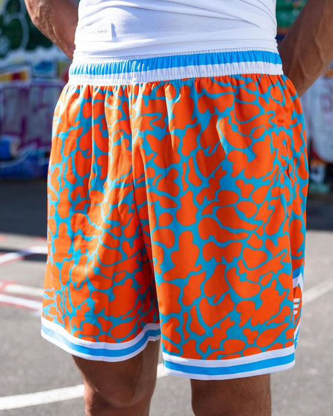 Model wearing orange and teal camo basketball shorts from Triple Threat