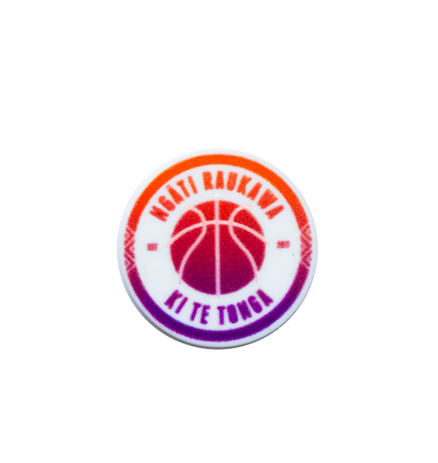 A circular basketball-themed Jibbitz charm with a gradient colour scheme from orange to purple. It features the text "NGATI RAUKAWA" at the top and "KI TE TONGA" at the bottom, encircling a basketball graphic in the centre